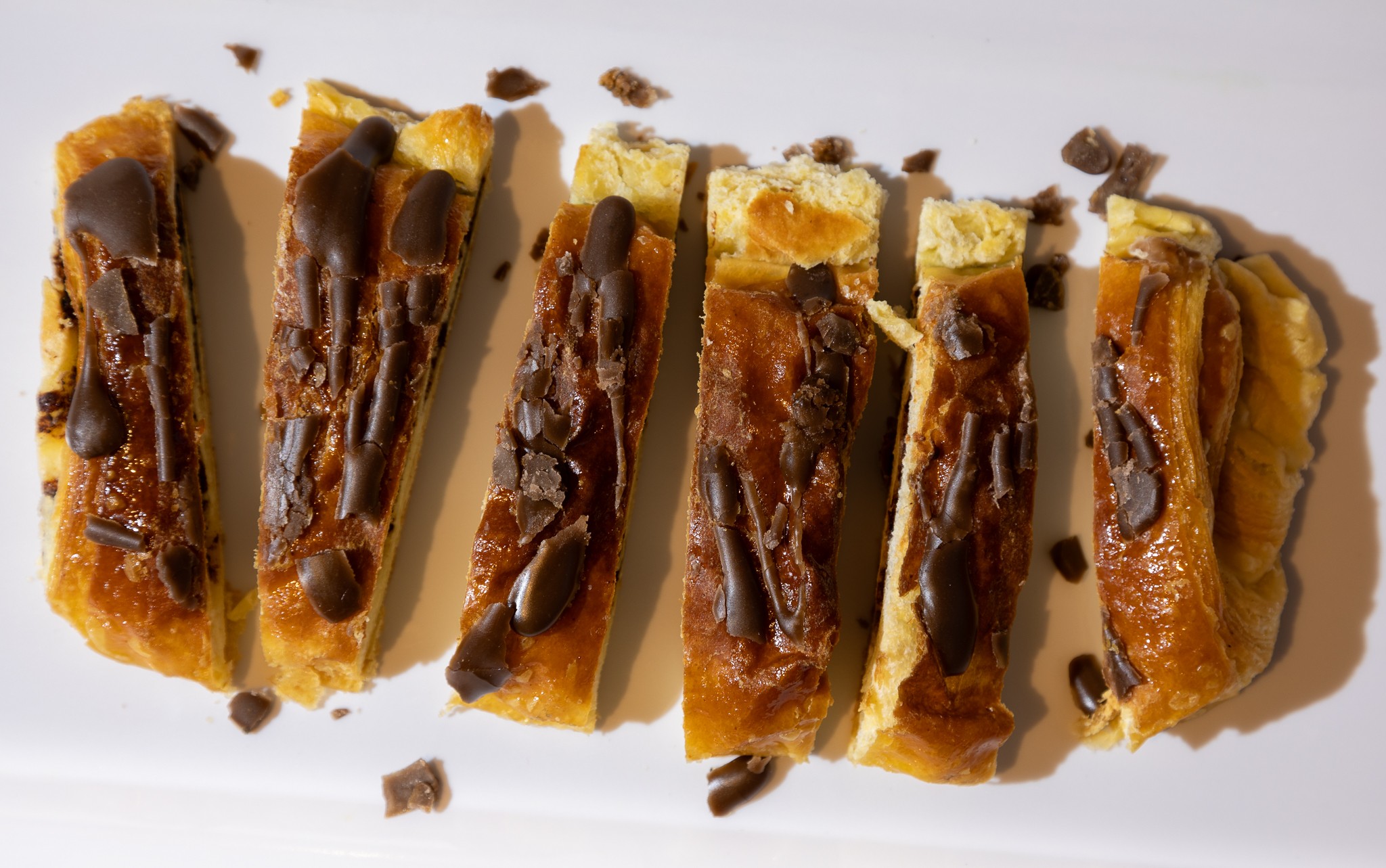Bright flat lay photograph of Chocolate Croissant sliced on a white plate. Upwey Village Bakery Project