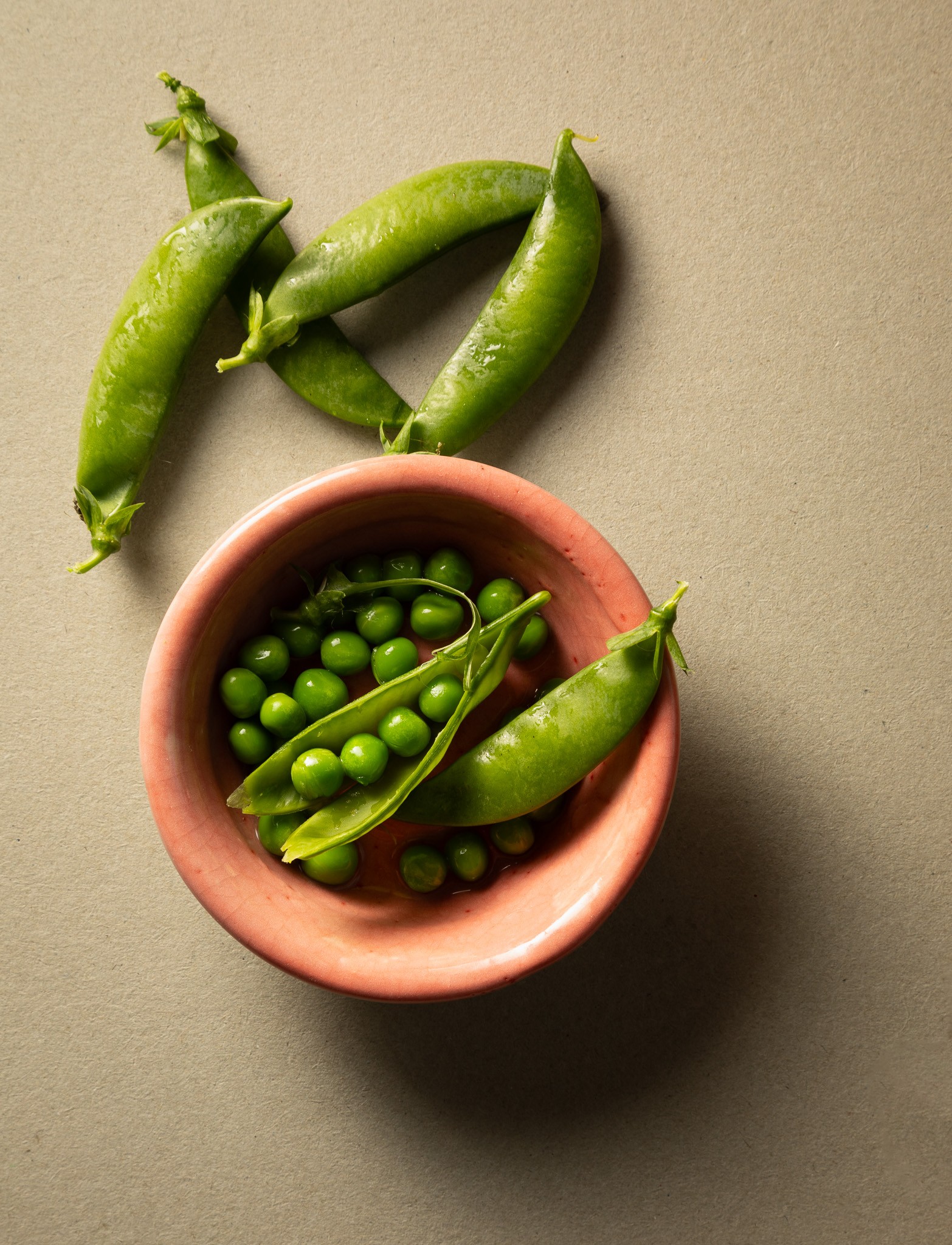 Photo of fresh green garden peas and pea pods in a salmon pink bowl.
Copyright Steve Wickenton Simply Food Photography
