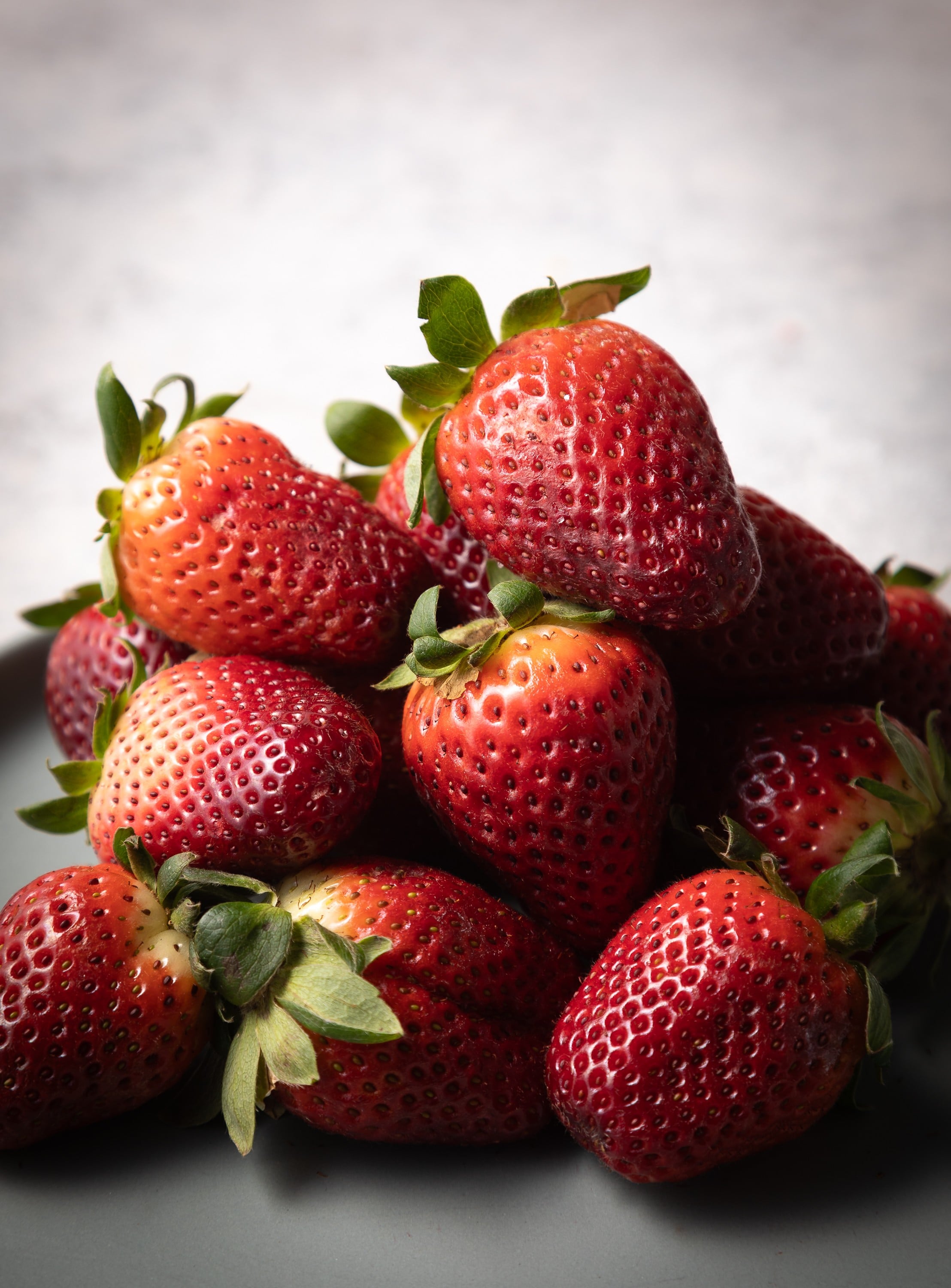 A photograph of fresh red juicy strawberries stacked on a bench by Steve Wickenton for Fresh Produce food photography project.