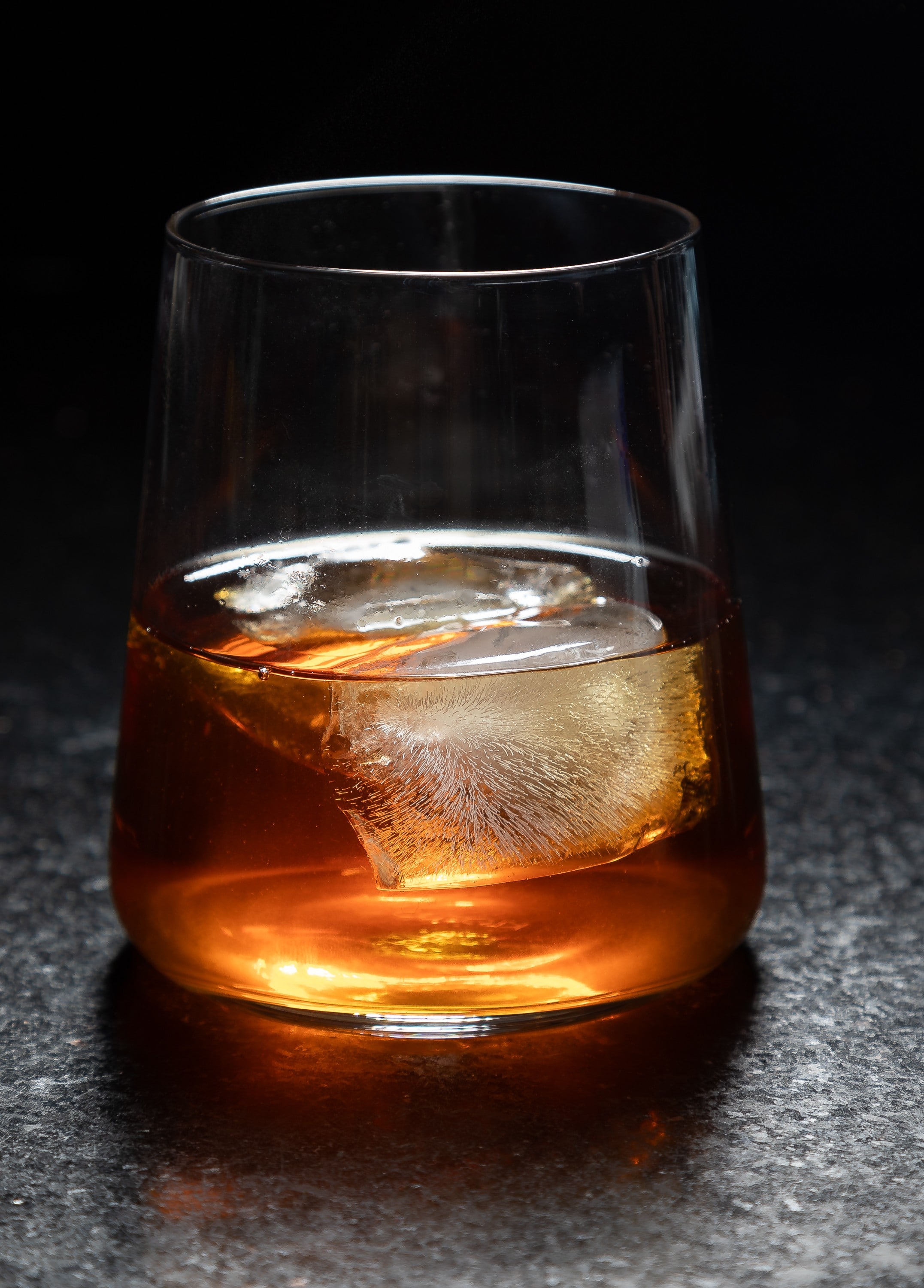 3 shots of whiskey on the rocks in a dark moody setting. by Steve Wickenton